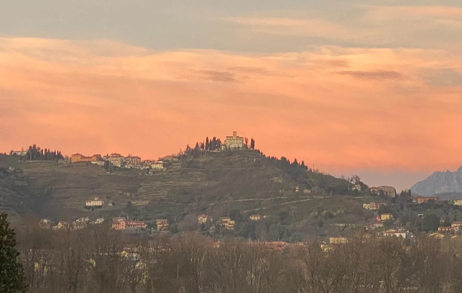 Montevecchia village along the ridge, with its sanctuary and terraced hillside beneath an orange sky